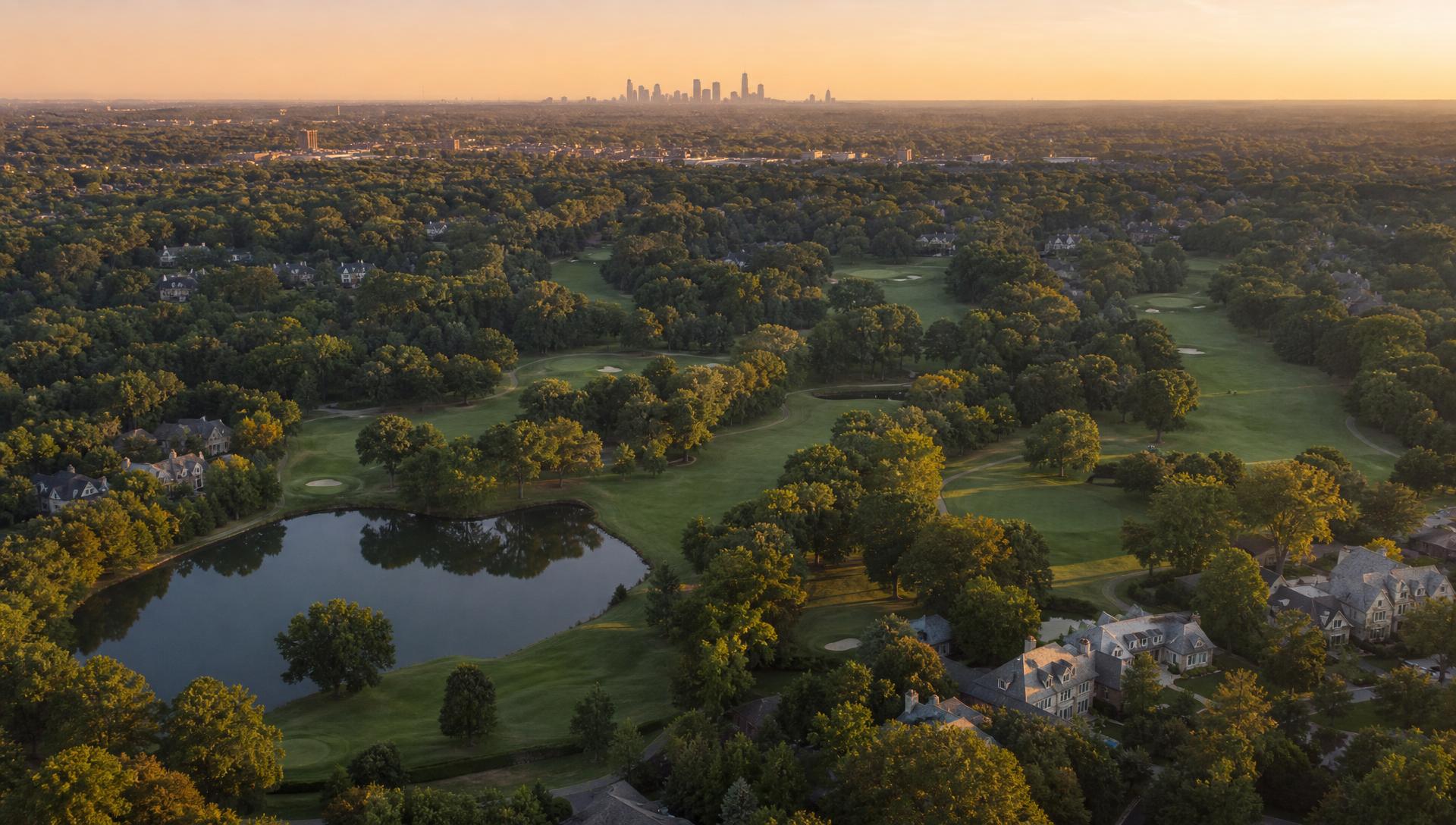 Aerial view of Providence Country Club at golden hour with the Dan Maples championship golf course, estate homes and mature oak trees